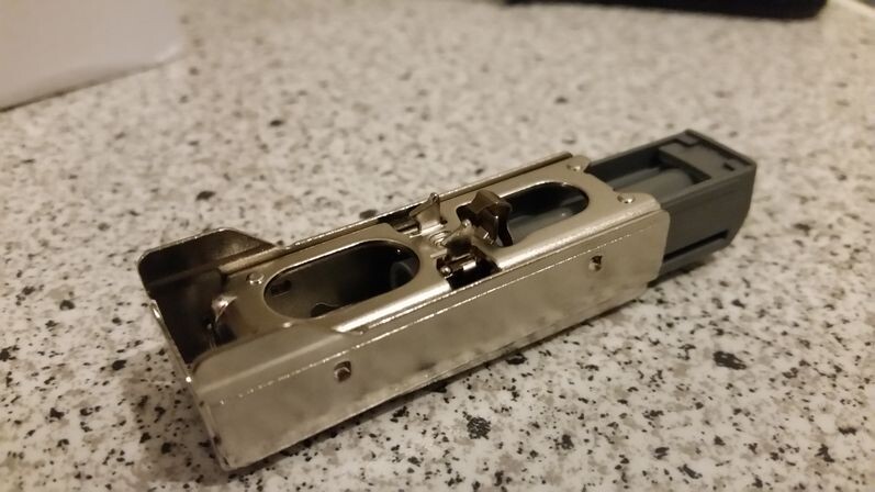 Metal rectangular component with two oval openings and black end piece on stone surface
