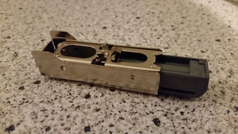 Metal adapter/plug with black plastic connector, lying on granite surface.