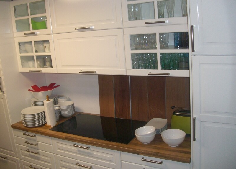 Modern kitchen with white cabinets, wooden countertop, induction cooktop, and dishes.