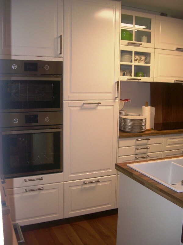 Modern kitchen with white cabinets, built-in ovens, open shelves, and sink on island.