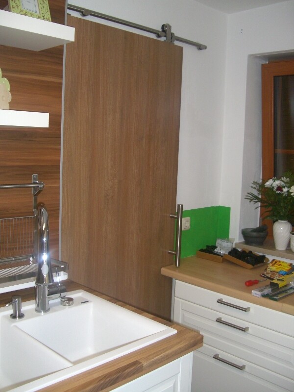 Kitchen with sink, wooden cabinet doors, countertop, and window; vase on the windowsill.