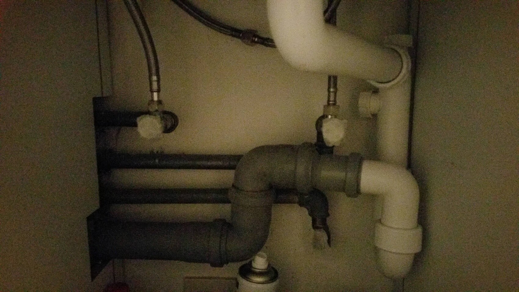 Pipes and plumbing connections visible under the sink.