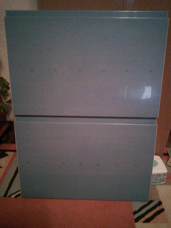 Two blue cabinet fronts stacked on top of each other in a room.