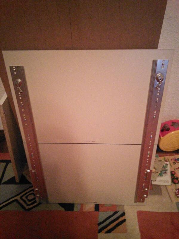 White furniture panel with side metal rails lying in a room