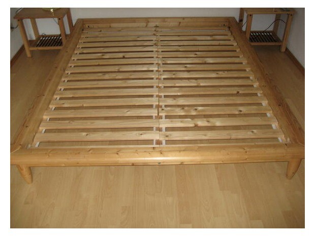 Wooden bed frame with slatted base in the bedroom, without mattress, on wooden floor