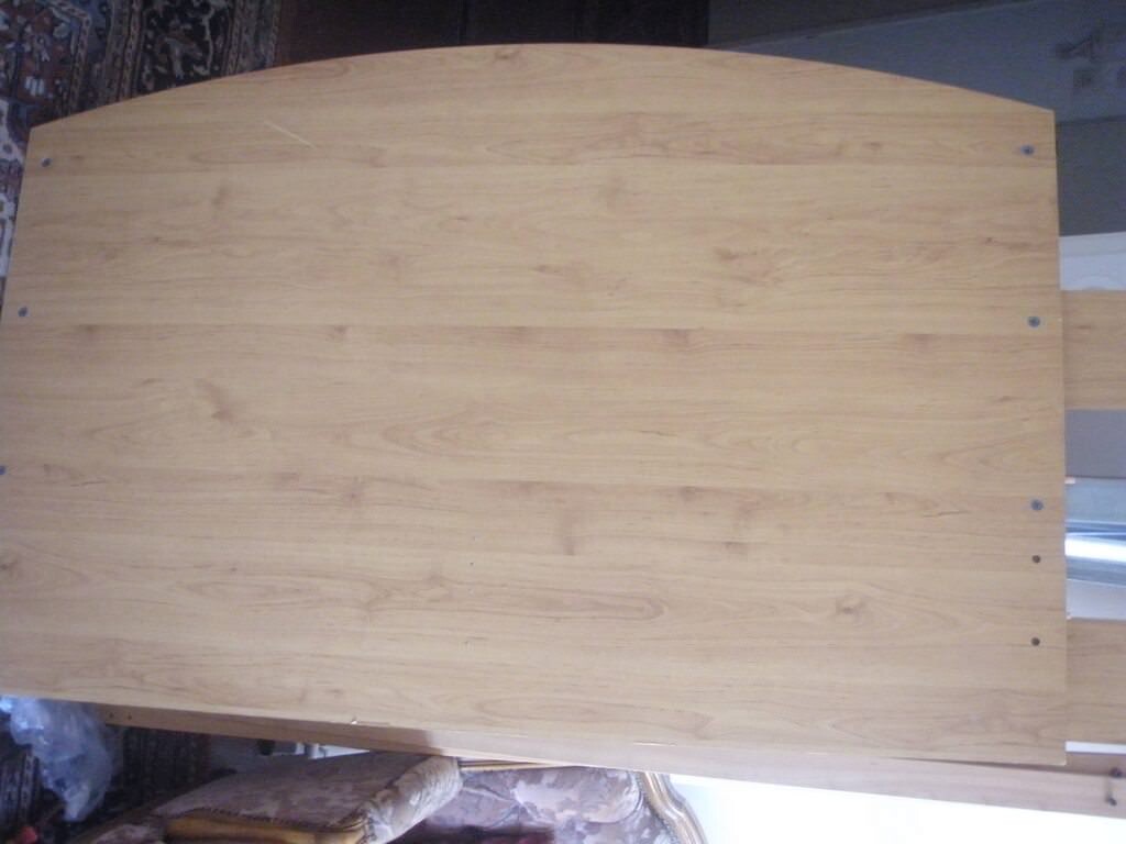 Wood table top with light grain and visible screws at the edge