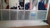 Small interior wardrobe with frosted glass fronts in front of window and picture wall.