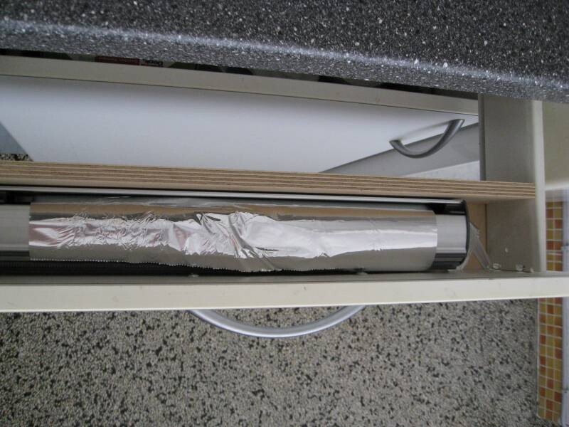 Pull-out kitchen cabinet drawer with aluminum foil roll and handle, granite countertop