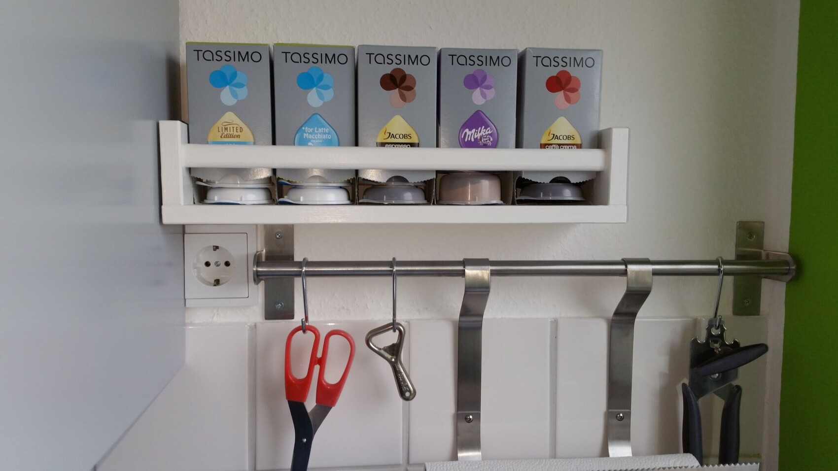 Kitchen rack with Tassimo coffee pods; below, a metal hook rail with scissors.