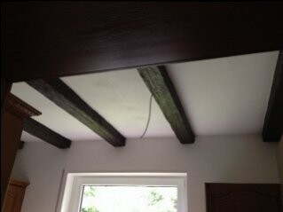 Room with exposed wooden beams on ceiling and window in the background
