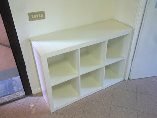 White cube shelf unit with open compartments in the hallway next to the door