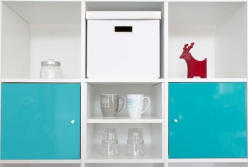Shelf with light blue doors, open compartments, and glasses in the middle.