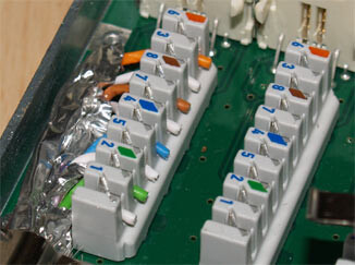 Close-up of white terminal blocks on a green circuit board with connectors