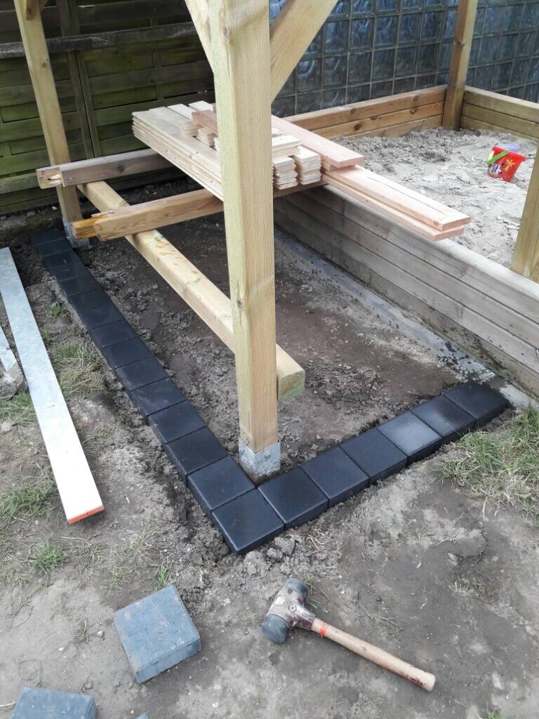 Foundation area with paving stones around a wooden structure during outdoor construction work