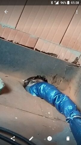 Blue plastic pipe installation through wall opening during construction work