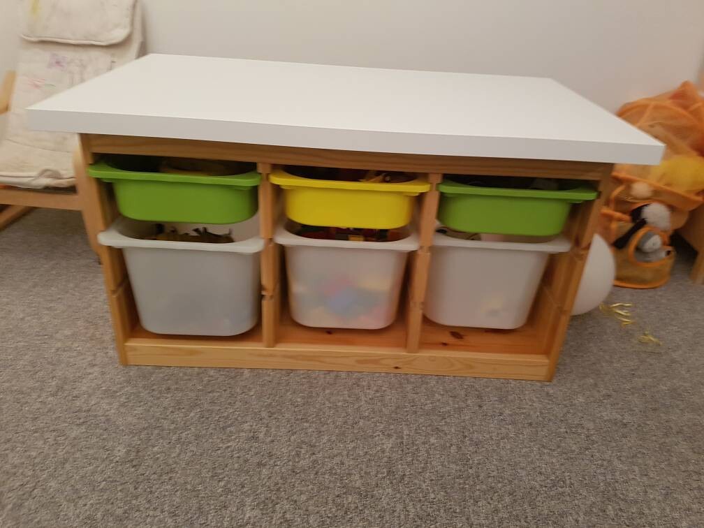 Wooden shelf with white top and three compartments, colorful boxes (green, yellow).