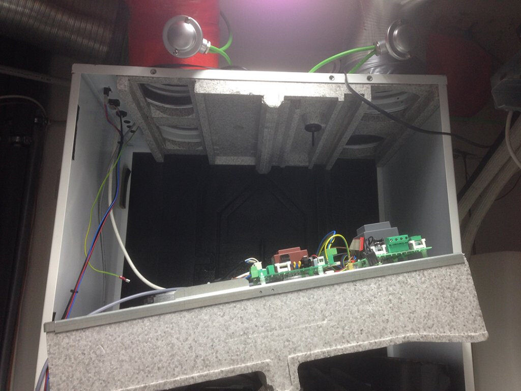 Open electronics cabinet with circuit boards, cables, and green terminal blocks.