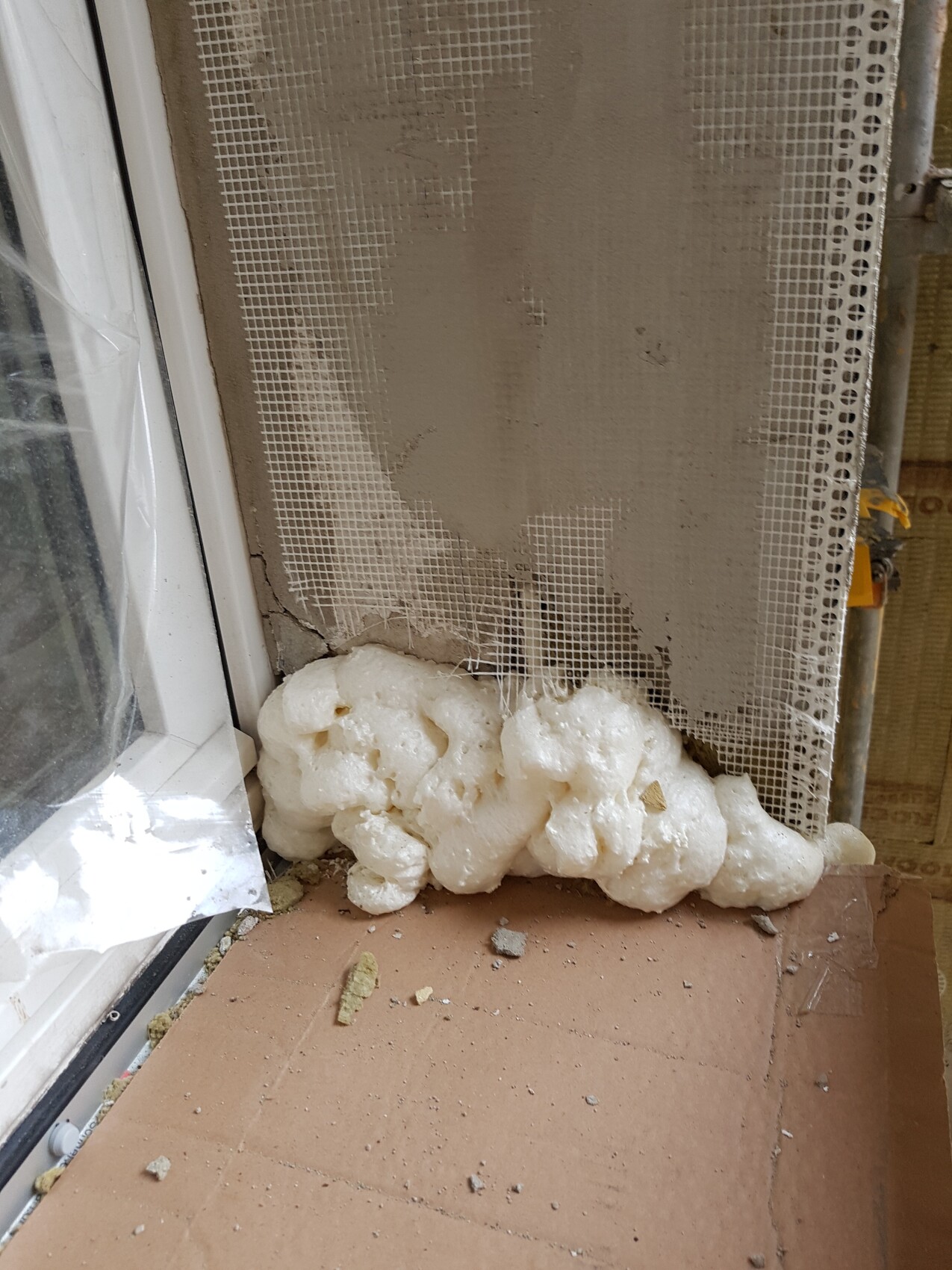 Construction site at window: wall with insulation foam and protective net