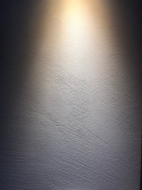 Rough wall with central spotlight, bright area in the middle and darker edges.