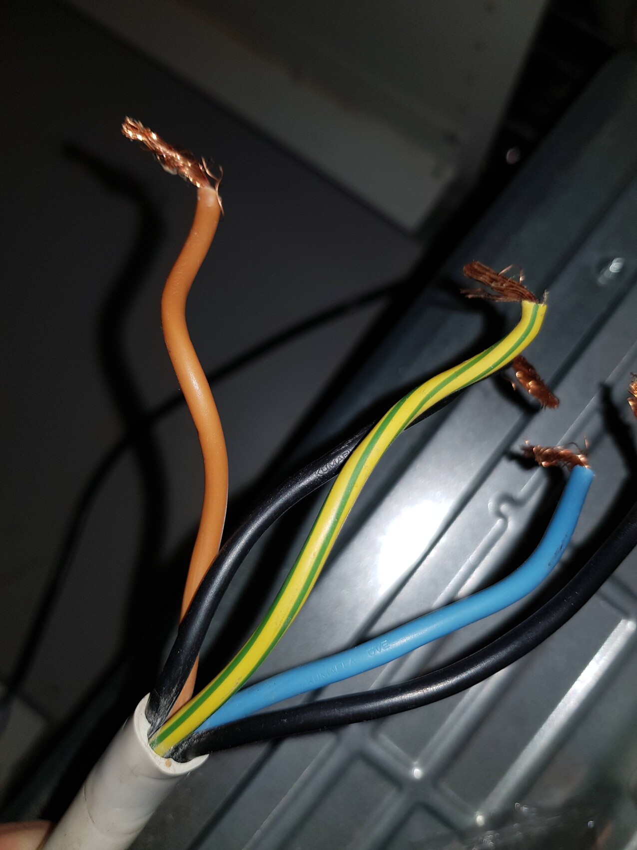 Exposed copper wire ends in colored cables (orange, blue, green-yellow) in a housing.