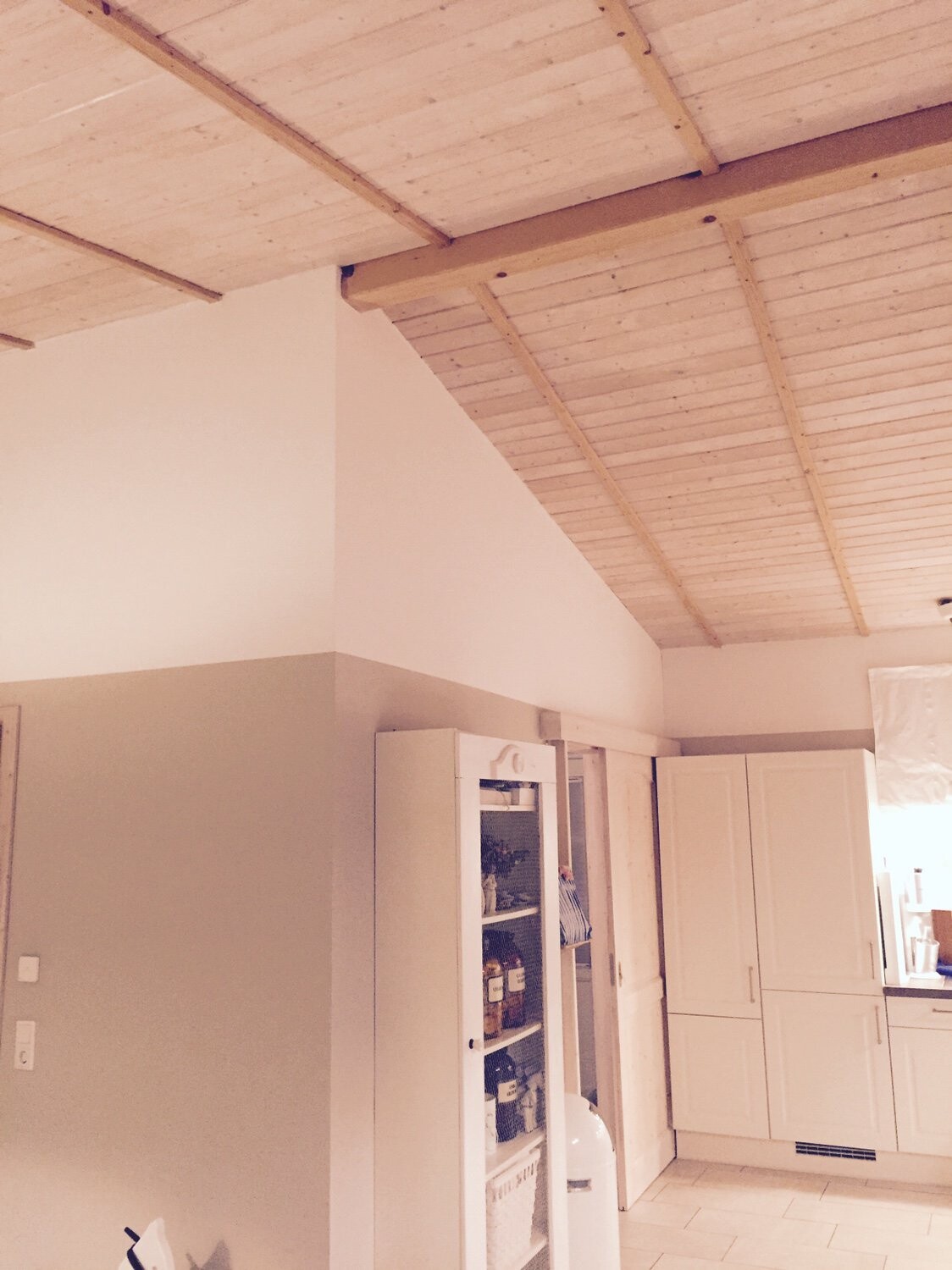 Kitchen with white cabinets, glass door cabinet, and visible wooden beam ceiling.