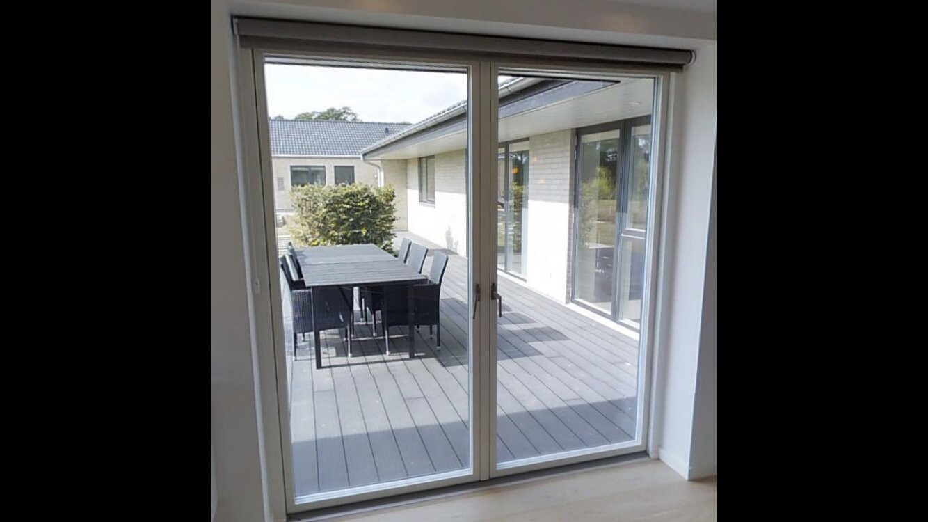 Open glass sliding door leading to a terrace with dining table and chairs outside.