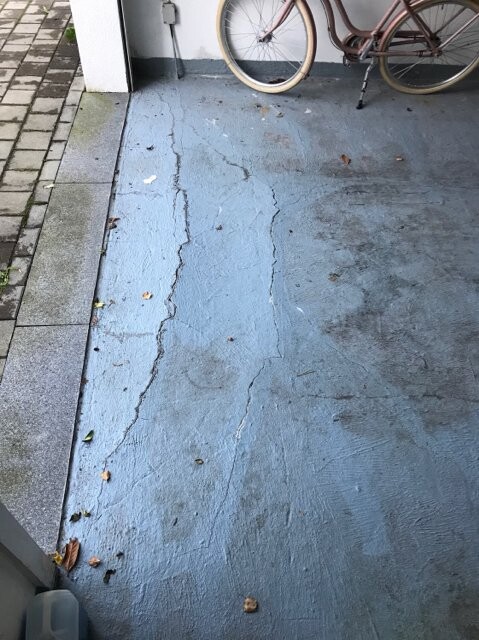 Outdoor area: blue painted, cracked concrete floor; a bicycle leaning in the background.