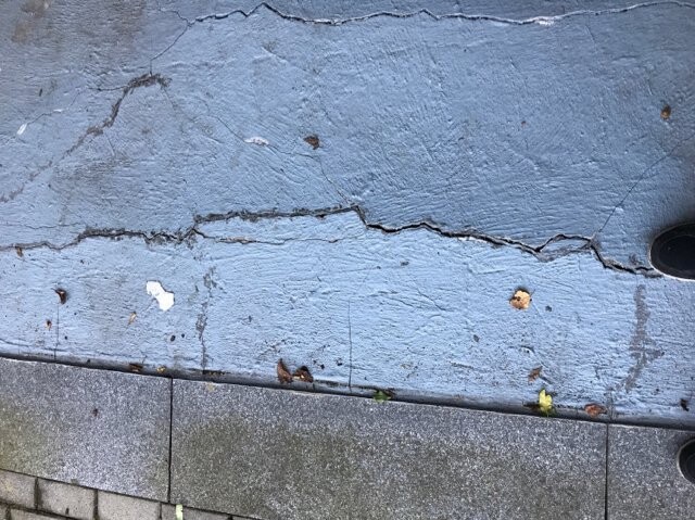 Cracked blue concrete surface with paving slabs, shoe at the right edge.