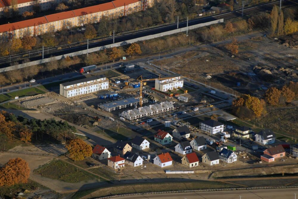 Aerial view of a construction site with a crane, new houses, and adjacent row houses in autumn.