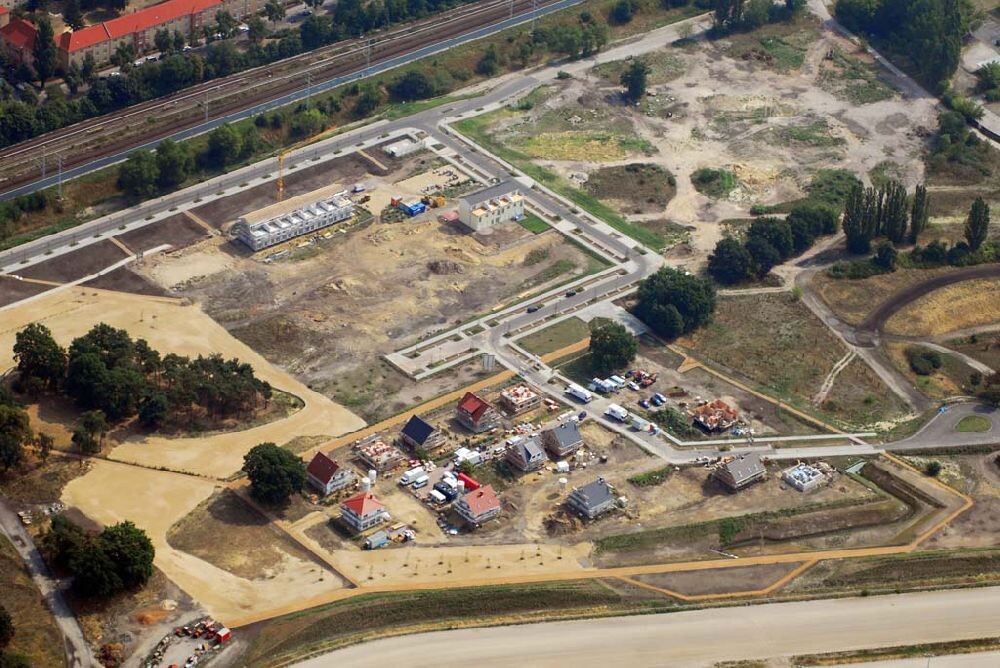 Aerial view of a construction area with new buildings, streets, trees, and red roofs.