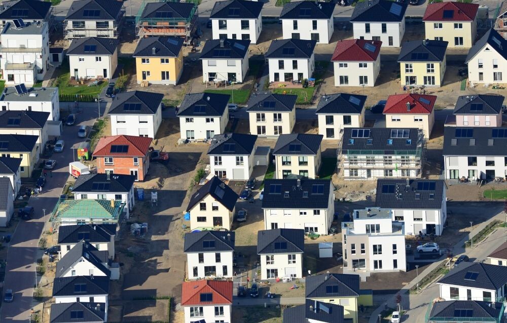 Aerial photo of a new residential neighborhood: many modern houses with dark roofs, streets, and vehicles.