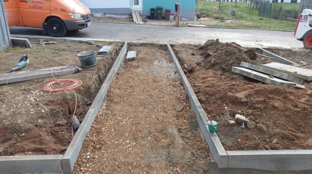 Construction site with excavated trenches, concrete foundations, construction tools and van in the background