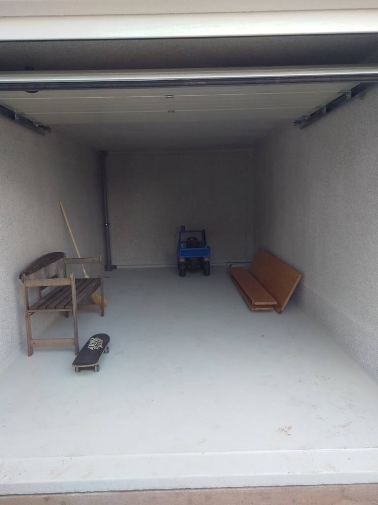 Empty garage with skateboard, wooden bench on the left, toy car at the back, and boards on the right.