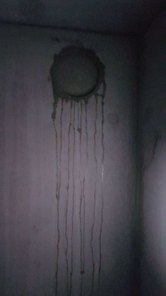 Dark interior with round dark staining on the wall and long drip marks running downward.