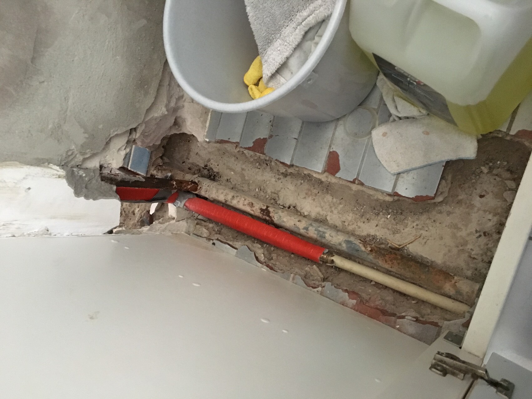 Open water pipes in bathroom floor during renovation.