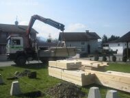 Construction site with crane excavator, timber components and preparations for the shell construction