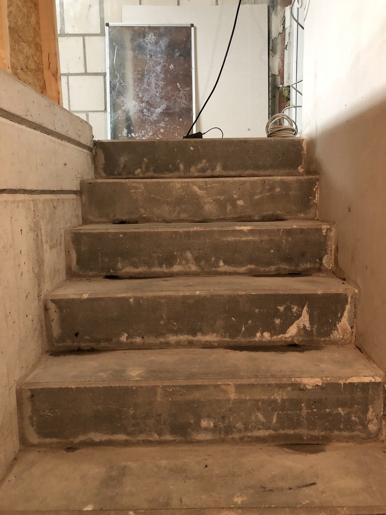 Basement steps under shell construction with cables and mirror in the background