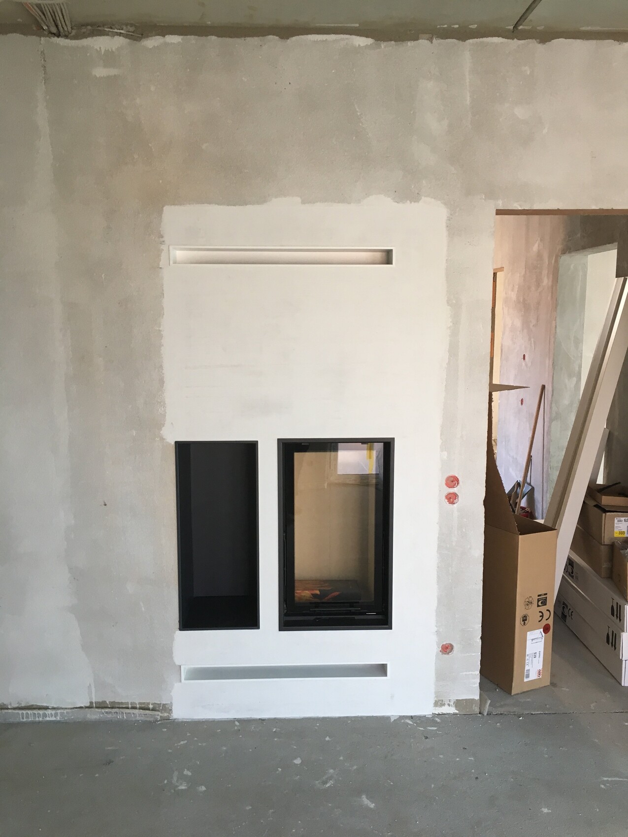 Construction site: White interior wall with two black niches; narrow on the left, larger with glass front on the right.