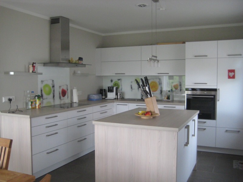 Modern kitchen with white cabinets, kitchen island, knife block and fruit basket, oven.