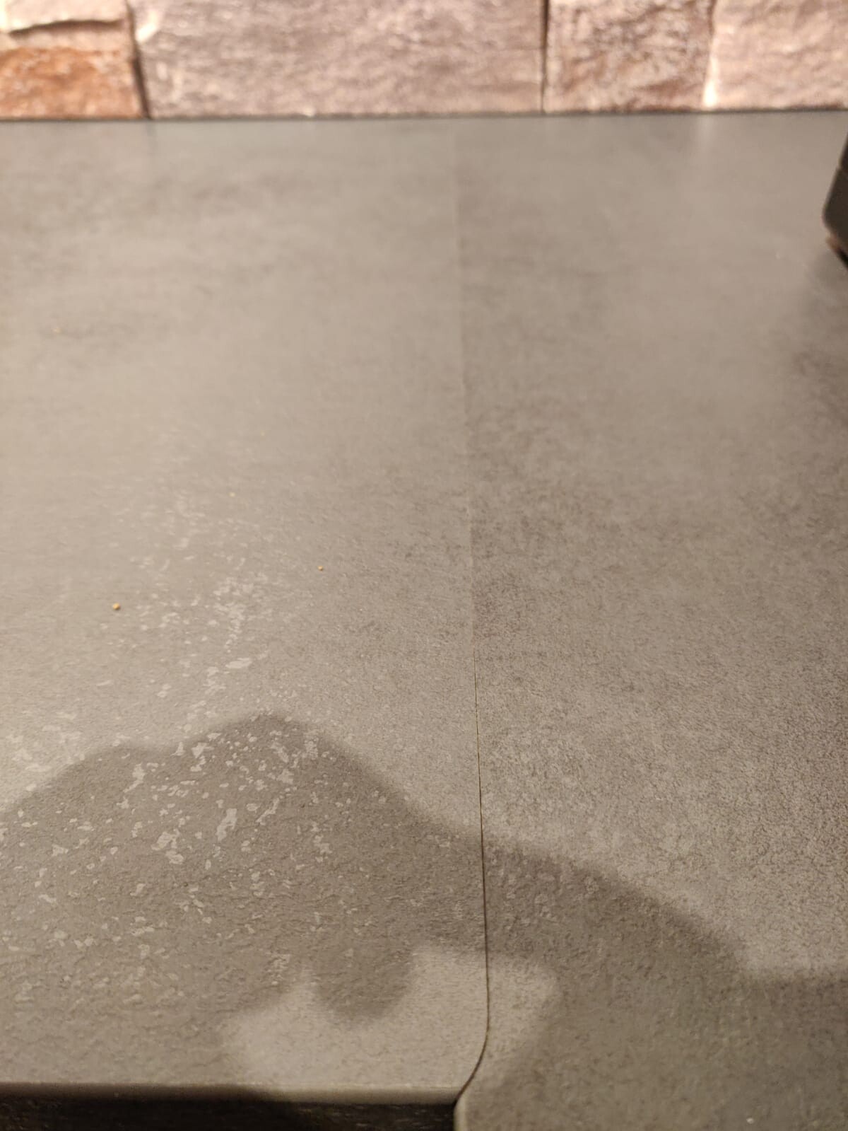 Close-up of gray floor tiles with brick wall in the background