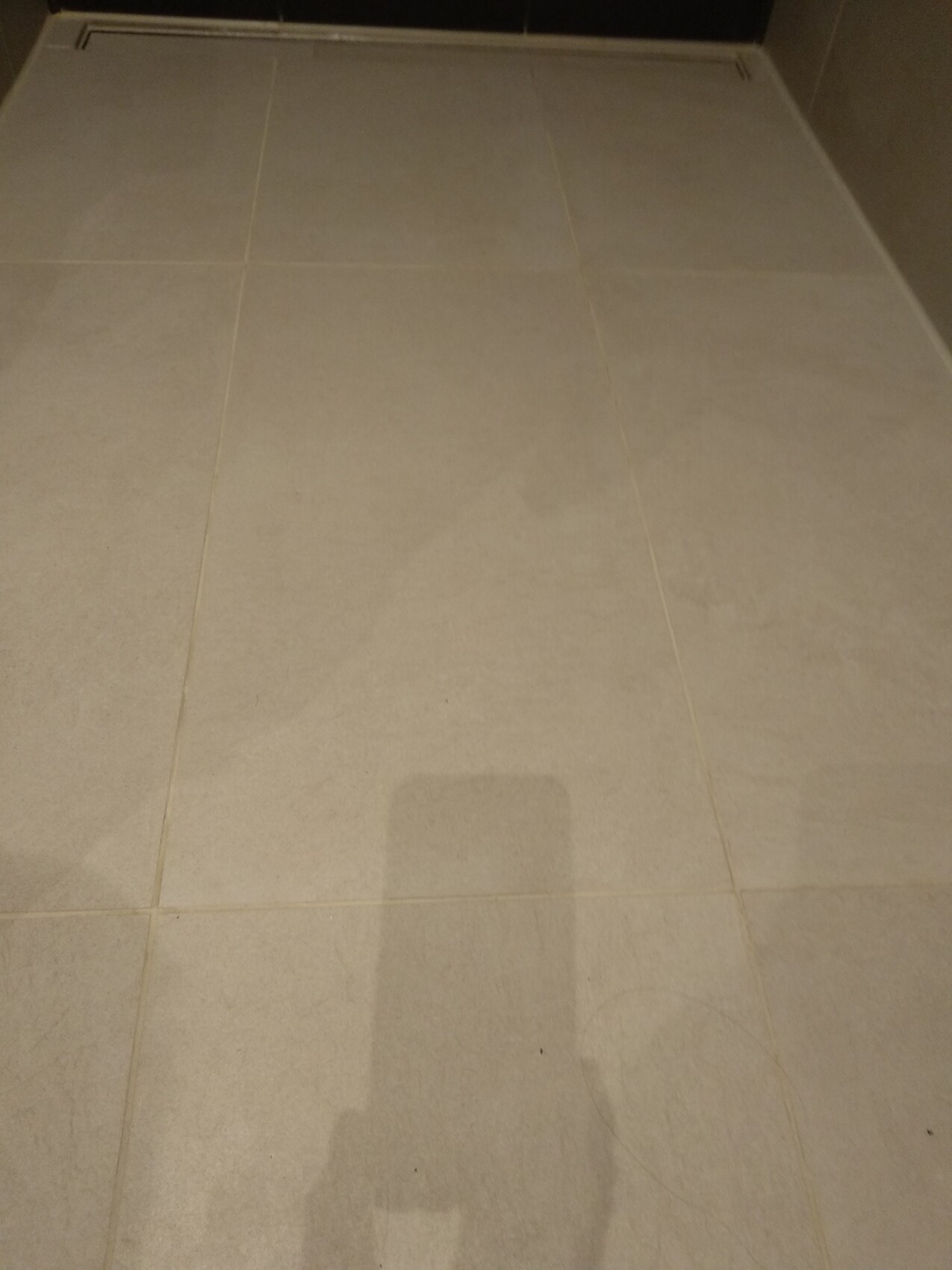 Beige floor tiles made of large rectangles, clean bathroom or hallway floor.
