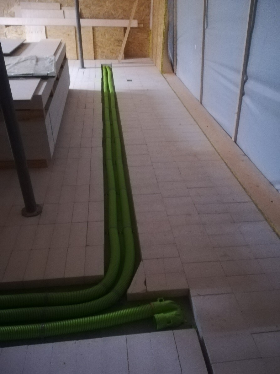 Interior of construction site: green flexible cable conduits running along floor and steps.