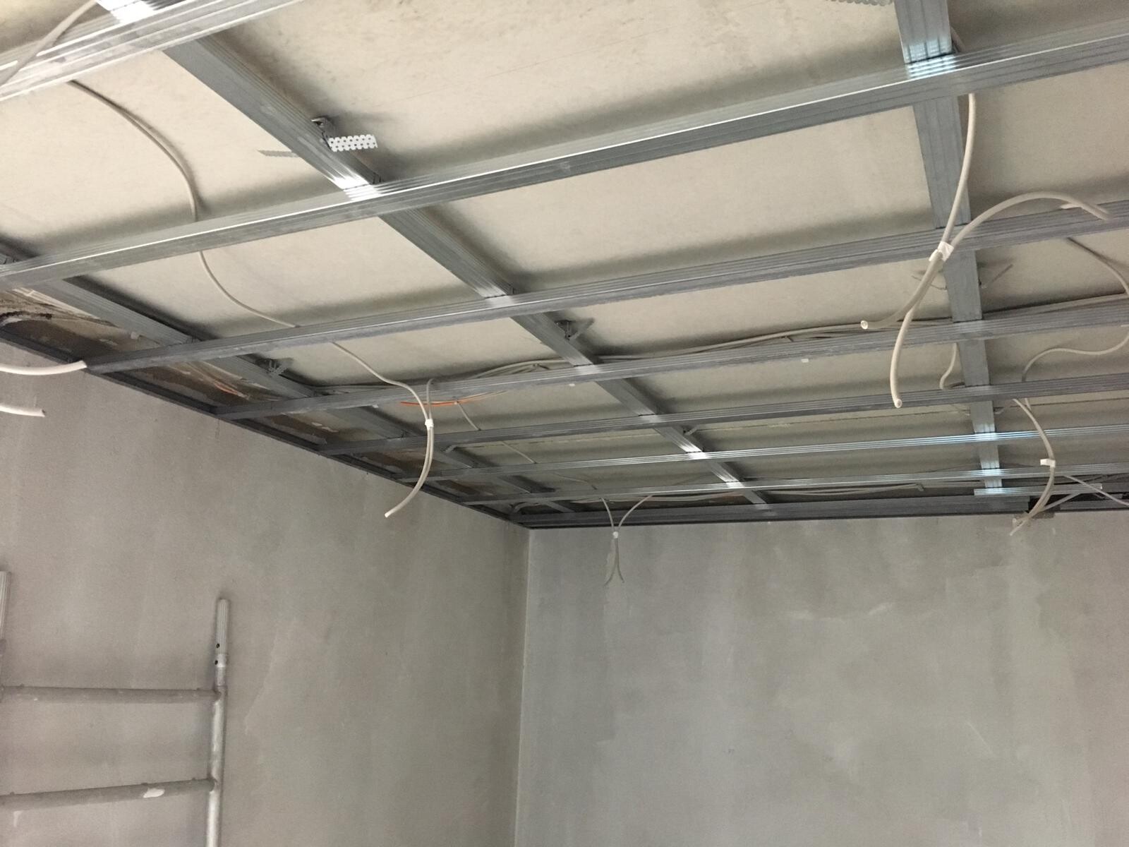 Open ceiling structure with metal beams and hanging cables in a shell construction.