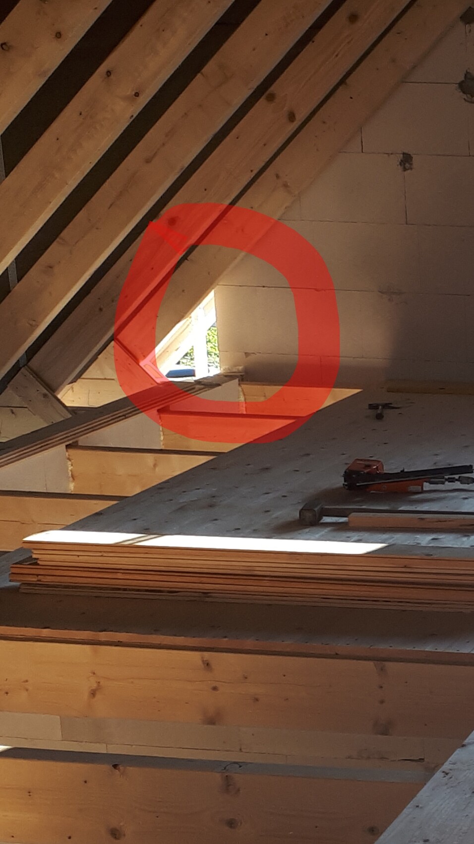 Construction work in the roof structure: visible wooden beams, wood panels, and tools, red circle marked.