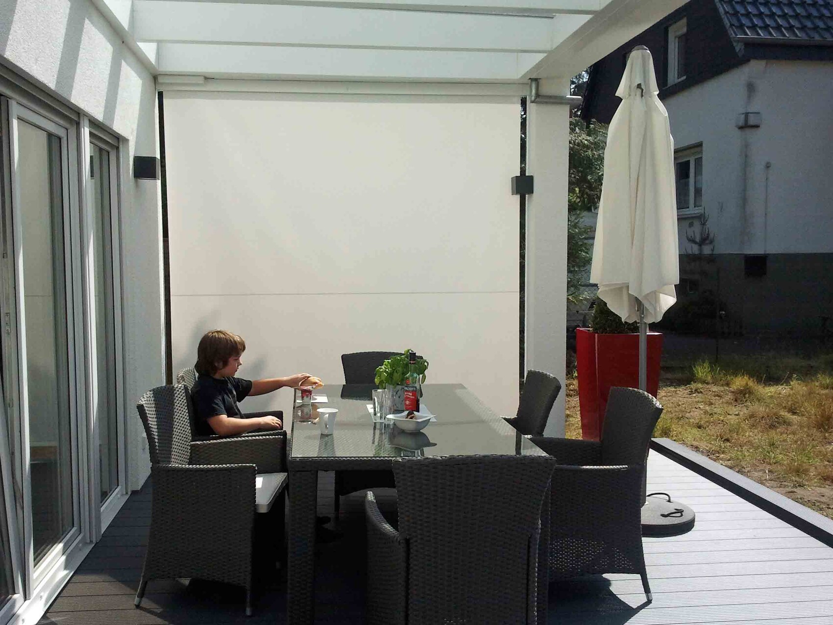 Terrace with glass roof, rattan dining set, parasol, boy sitting at table
