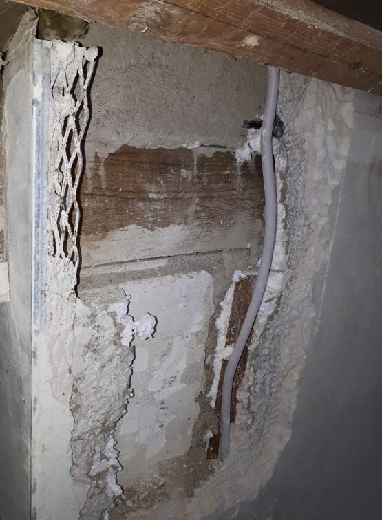 Basement wall with cracks, moisture and installation pipe visible
