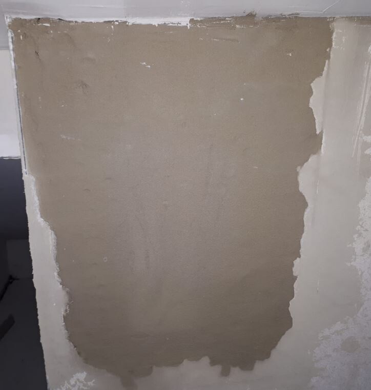 Interior wall with fresh plaster area and uneven surface.