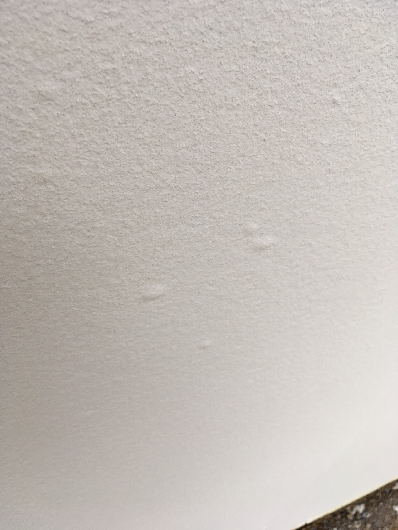 Close-up of a white, textured wall surface with slight roughness.