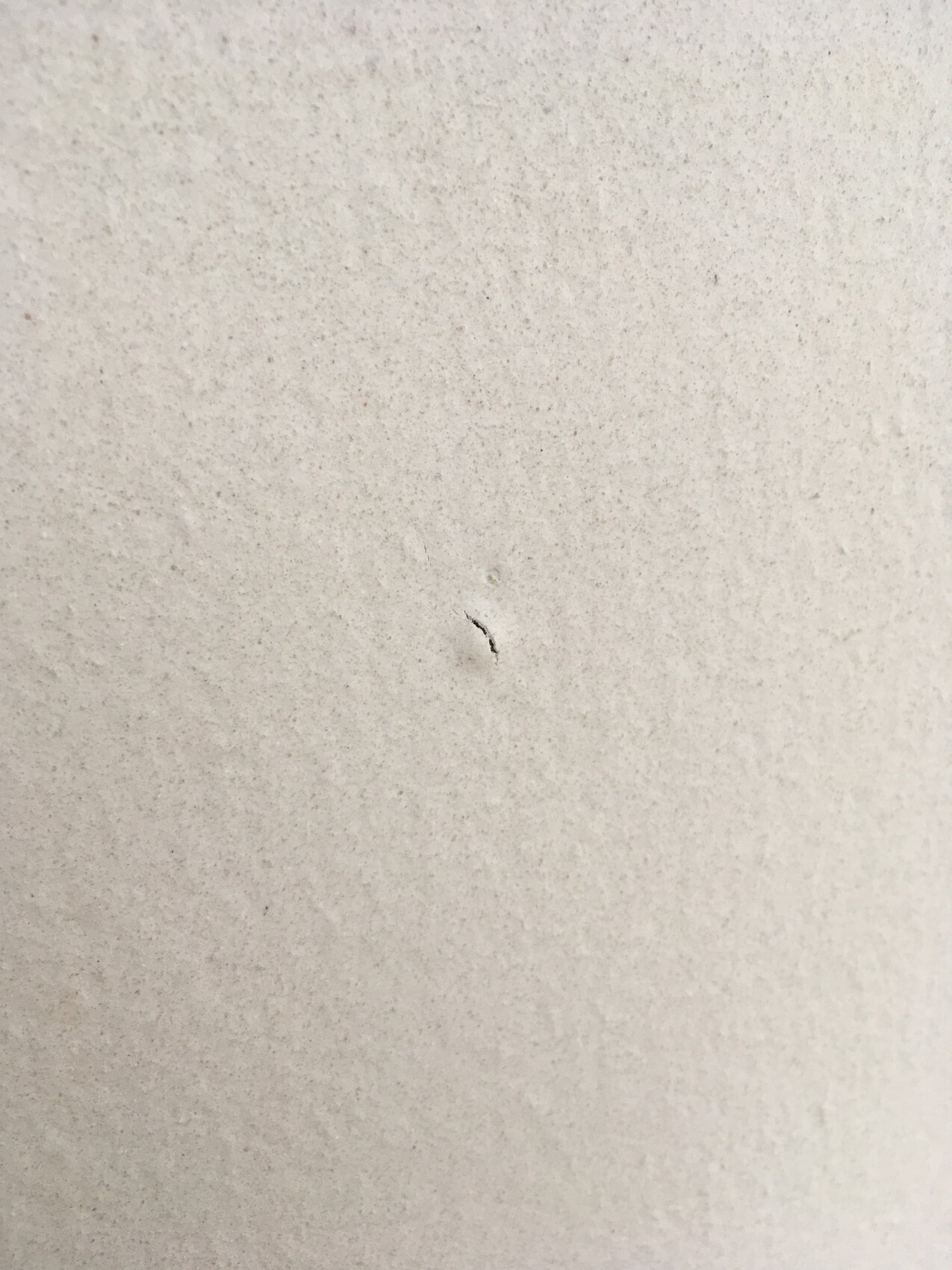Close-up of a light gray concrete surface with a small crack.