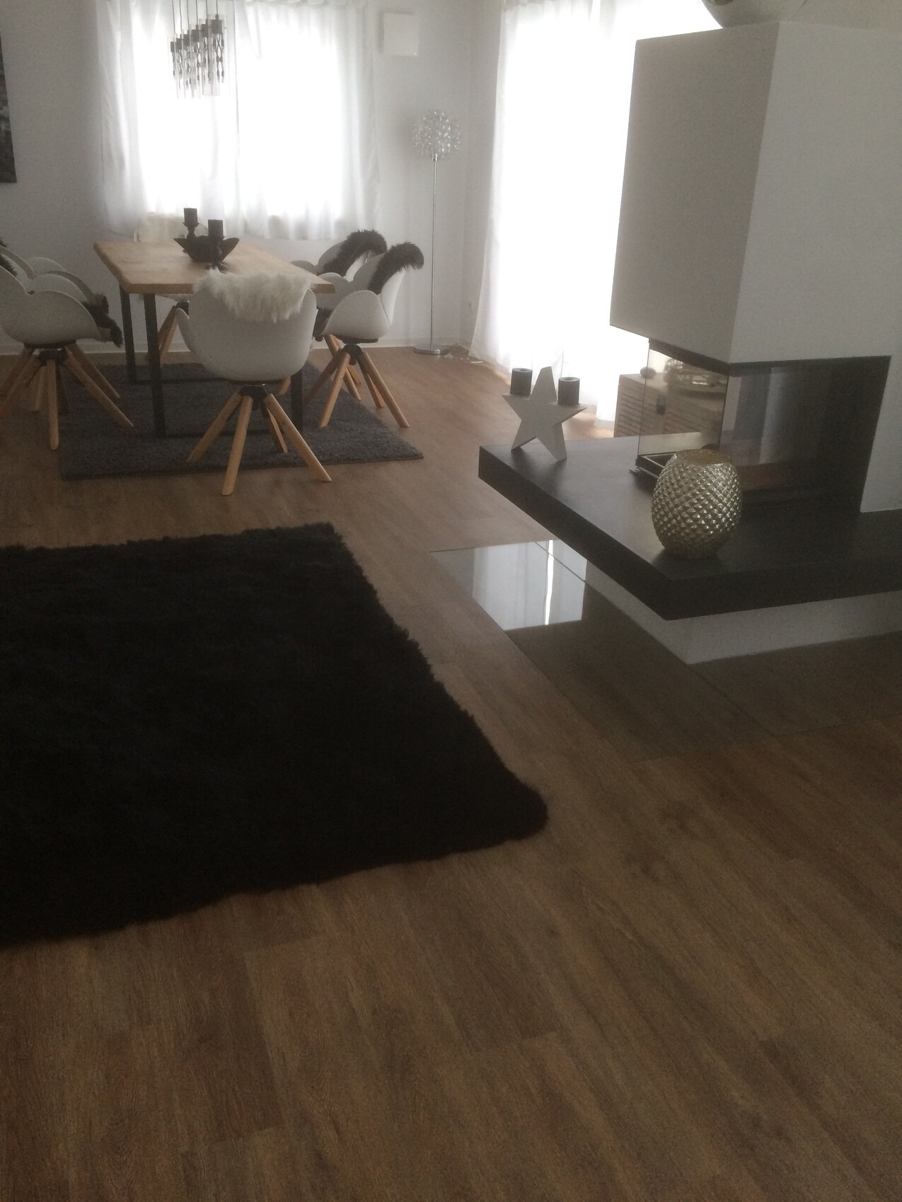 Moderner Essbereich im Wohnzimmer mit Kamin, Holzboden und weißen Sesseln
